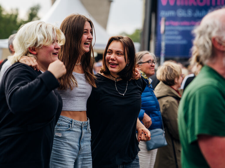 Das Bild zeigt drei junge Menschen auf dem Jubiläumsfestival der GLS Bank. Alle lachen.