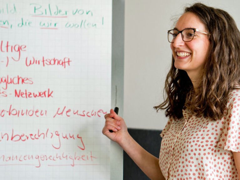 Eine Frau steht vor einem Flipchart mit Notizen.