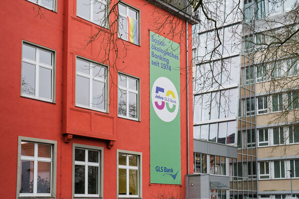 Außenansicht des GLS Bank Hauptgebäudes in Bochum. Rot mit einem Werbebanner.