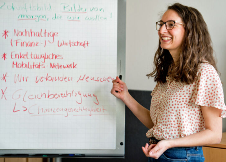 Eine Mitarbeiterin steht an einem Flipchart, auf dem sie schon Punkte notiert hat.