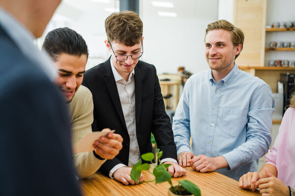 Das Bild zweigt mehrere Junge Menschen am Tisch im Gespräch.