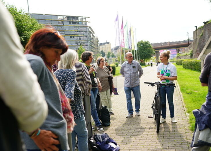 Menschen stehen bei einem Fahrradworkshop auf einem Vorplatz zusammen.