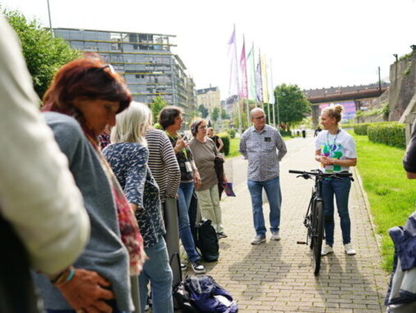 gls-bank-nachhaltigkeitsbericht-2023-jahresversammlung-radworkshop Menschen stehen bei einem Fahrradworkshop auf einem Vorplatz zusammen.